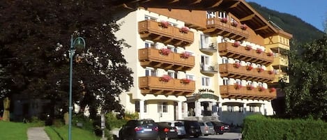 A multi-story hotel with wooden balconies, a clear sky, and a mountain backdrop.