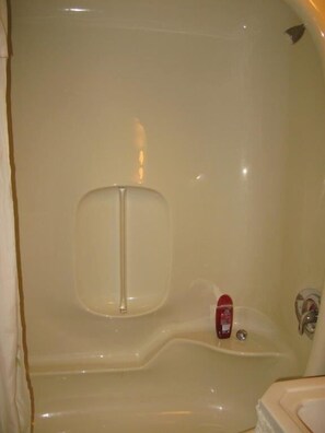 A bathroom with a bathtub, a small red soap dispenser, and a mirror. - Country Comfort Bed & Breakfast (Golden)