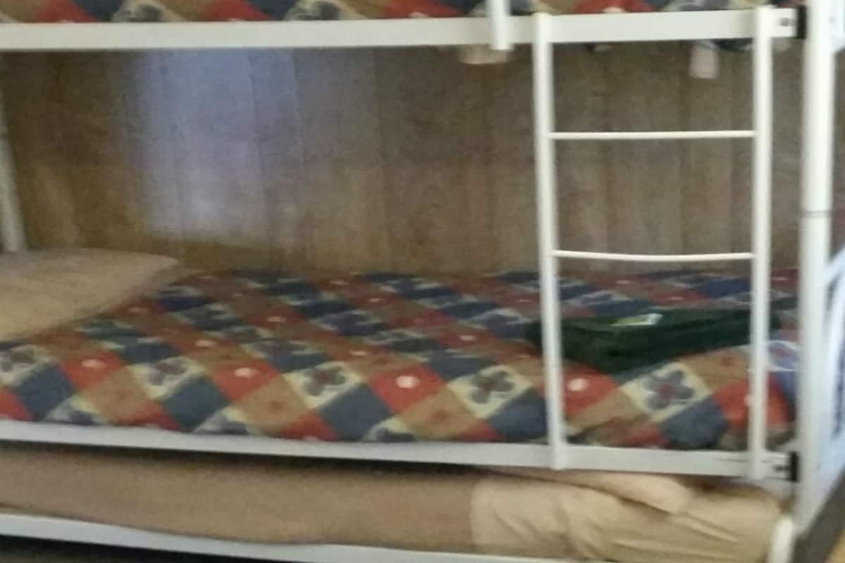 Een stapelbed met een kleurrijke quilt en een ladder.