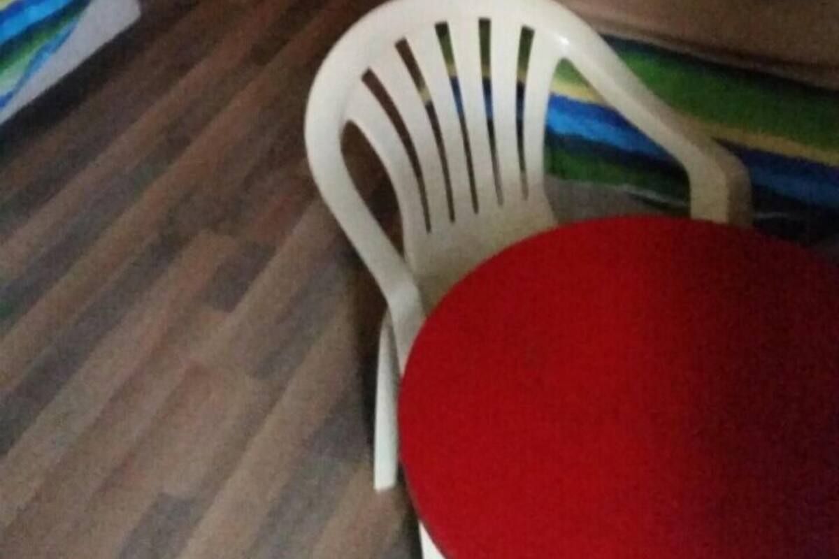 Een houten kamer met stapelbedden, een kleine tafel en een witte plastic stoel.