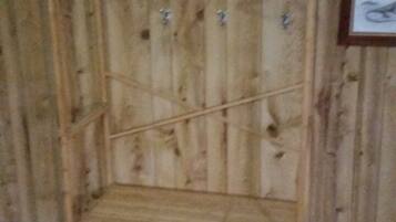A wooden wardrobe with multiple shelves and hanging space, set against a wooden wall.
