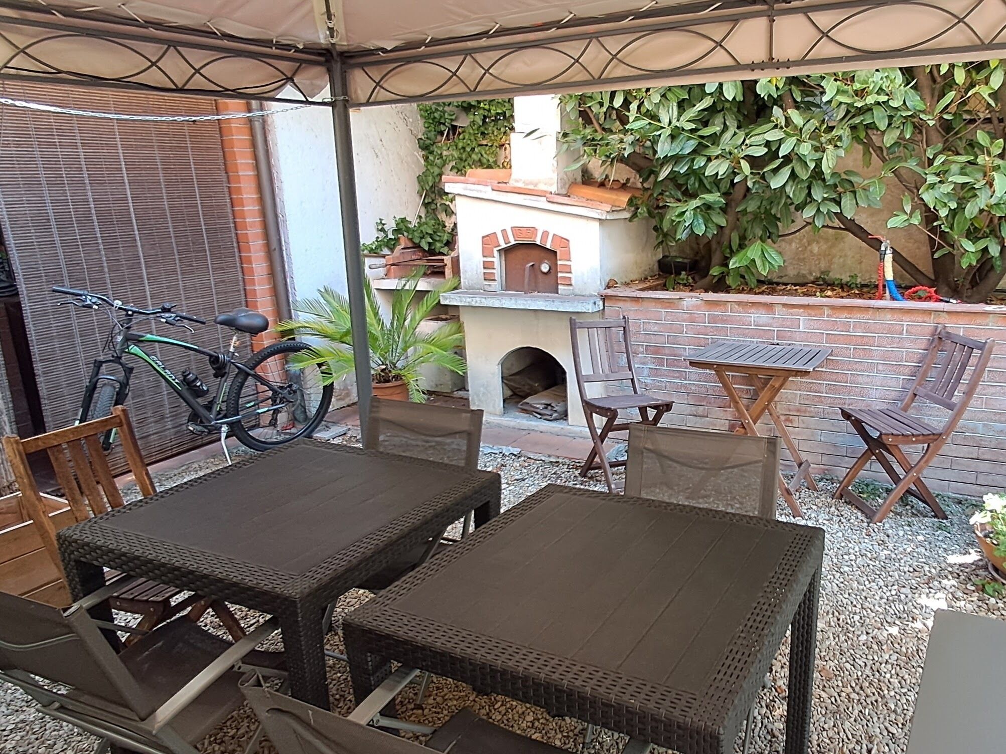 Un patio al aire libre con una parrilla de ladrillo, asientos y una bicicleta.