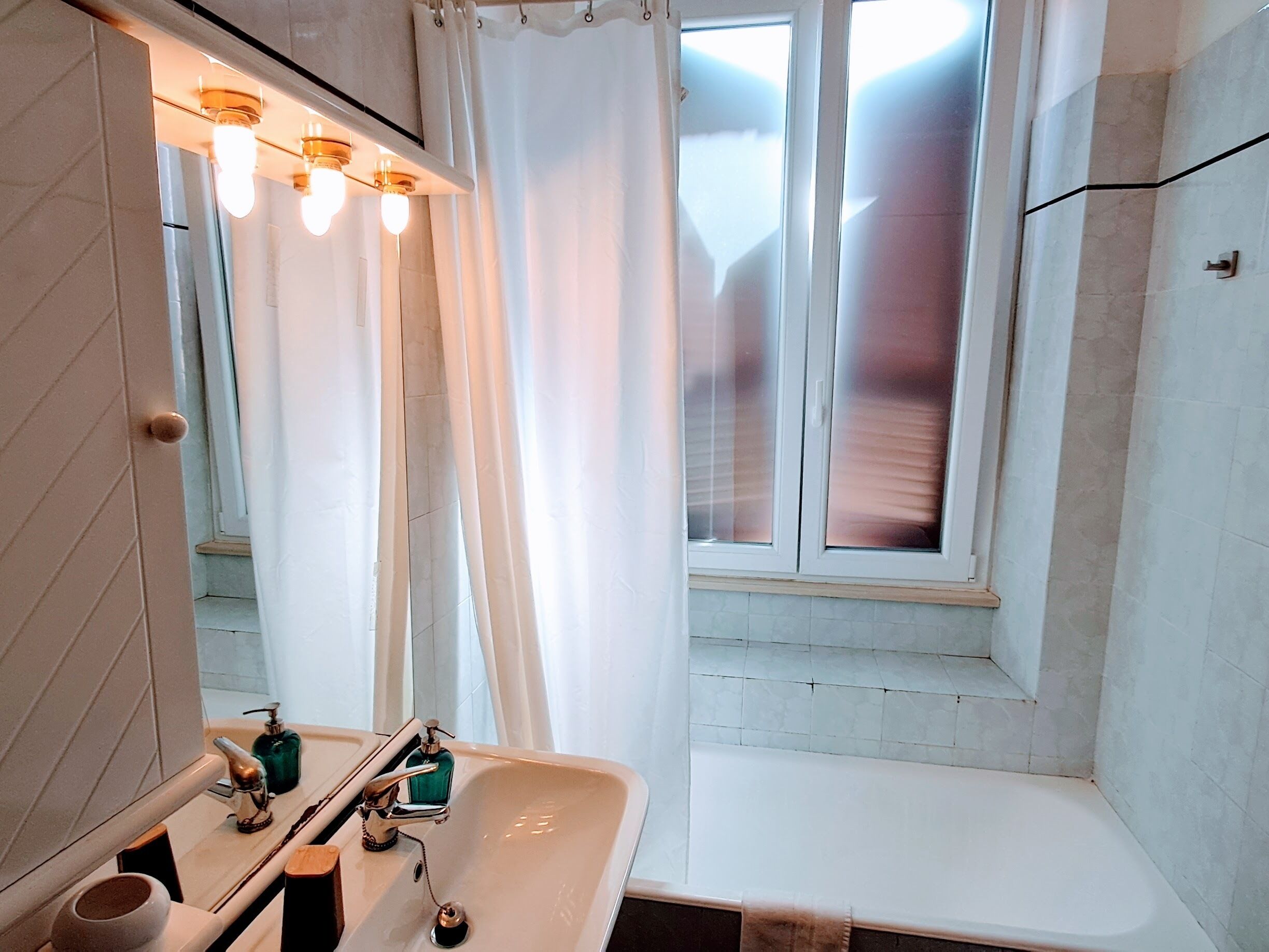 Un baño con lavabo, espejo y ventana.