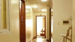 A hotel hallway with a checkered floor pattern, a wooden door on the left, and a metal railing on the right. - Hoa Lu Hotel 2 (Ninh Binh)