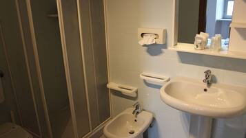 A bathroom with a toilet, bidet, sink, and a mirror.