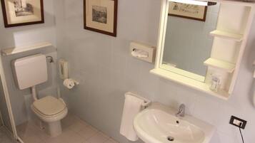 Een badkamer met toilet, wastafel en foto's in een lijst.