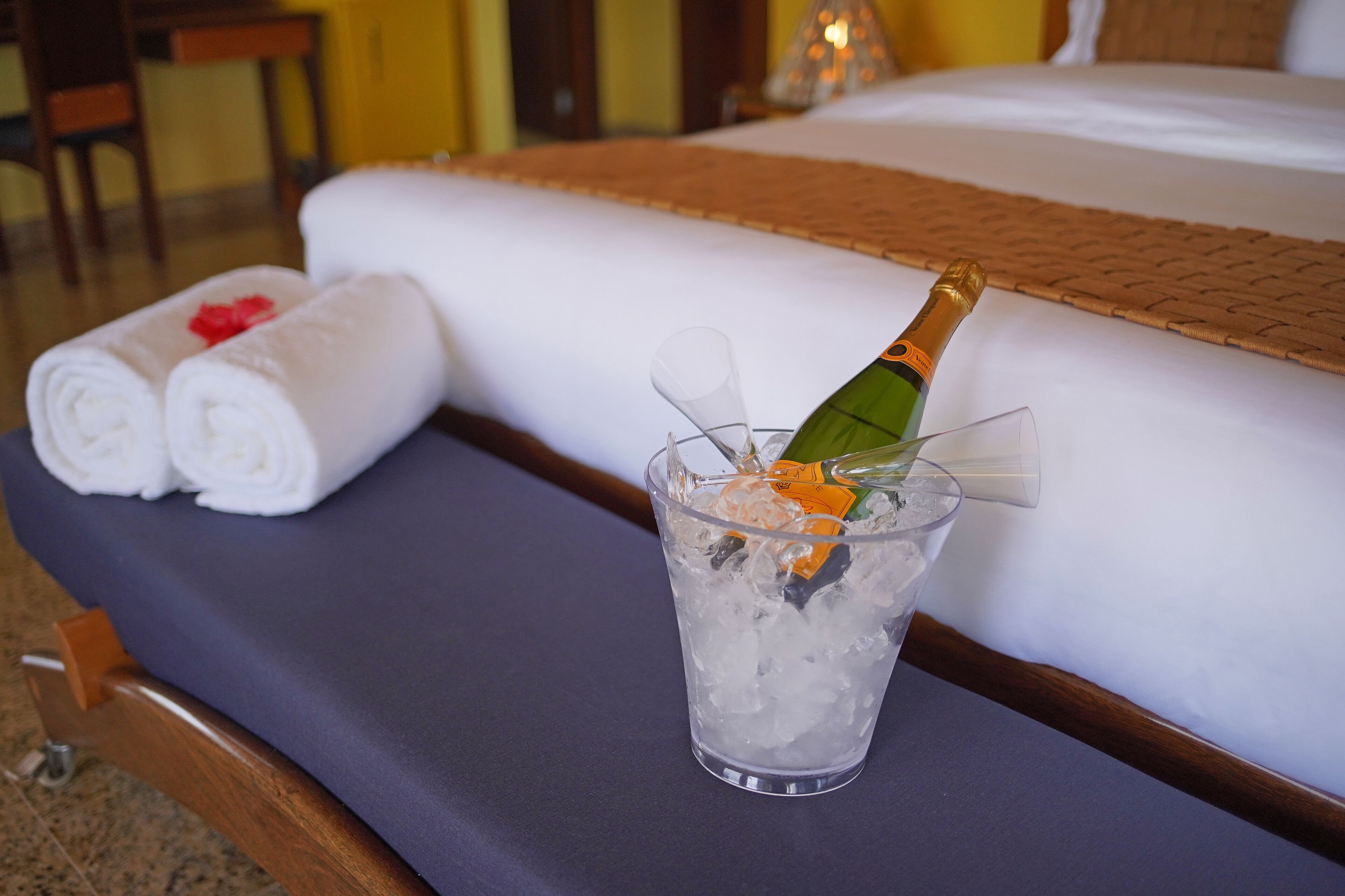 A bed with a bottle of champagne in a glass of ice.
