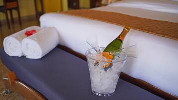 A bed with a bottle of champagne in a glass of ice.