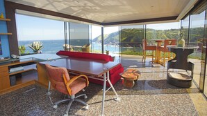 Una oficina moderna con un escritorio grande, un sofá rojo y vistas al océano.