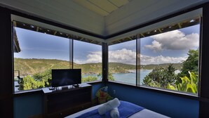 Un dormitorio con un ventanal que ofrece vistas a un lago y colinas.