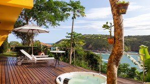A wooden deck with a hot tub, lounge chairs, and a table with an umbrella.