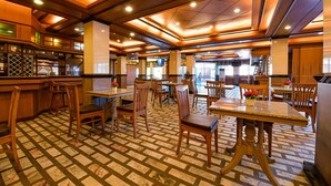 Ein Restaurant mit Holztischen, einem gemusterten Boden und einem modernen Deckenbau.
