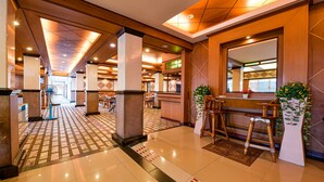 Eine Hotelhalle mit Empfangstresen, Sitzgelegenheiten und einer Rezeption.