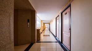 Ein langer, schmaler Hotelkorridor mit Marmorwand auf der einen Seite und einer Tür auf der anderen.