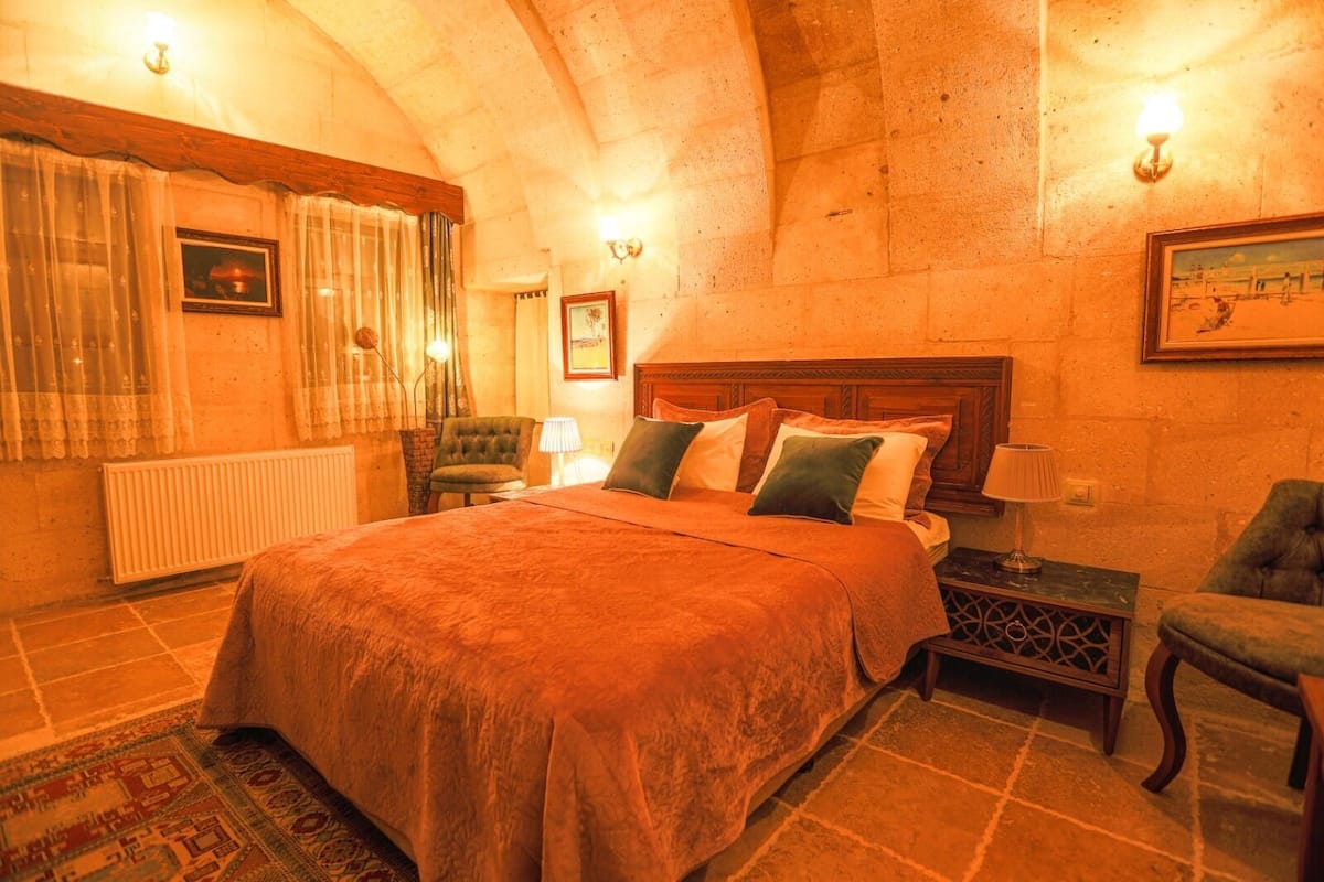 Ein gemütliches Schlafzimmer mit einem großen Bett, einem Sessel, einem Nachttisch und einer Heizung.