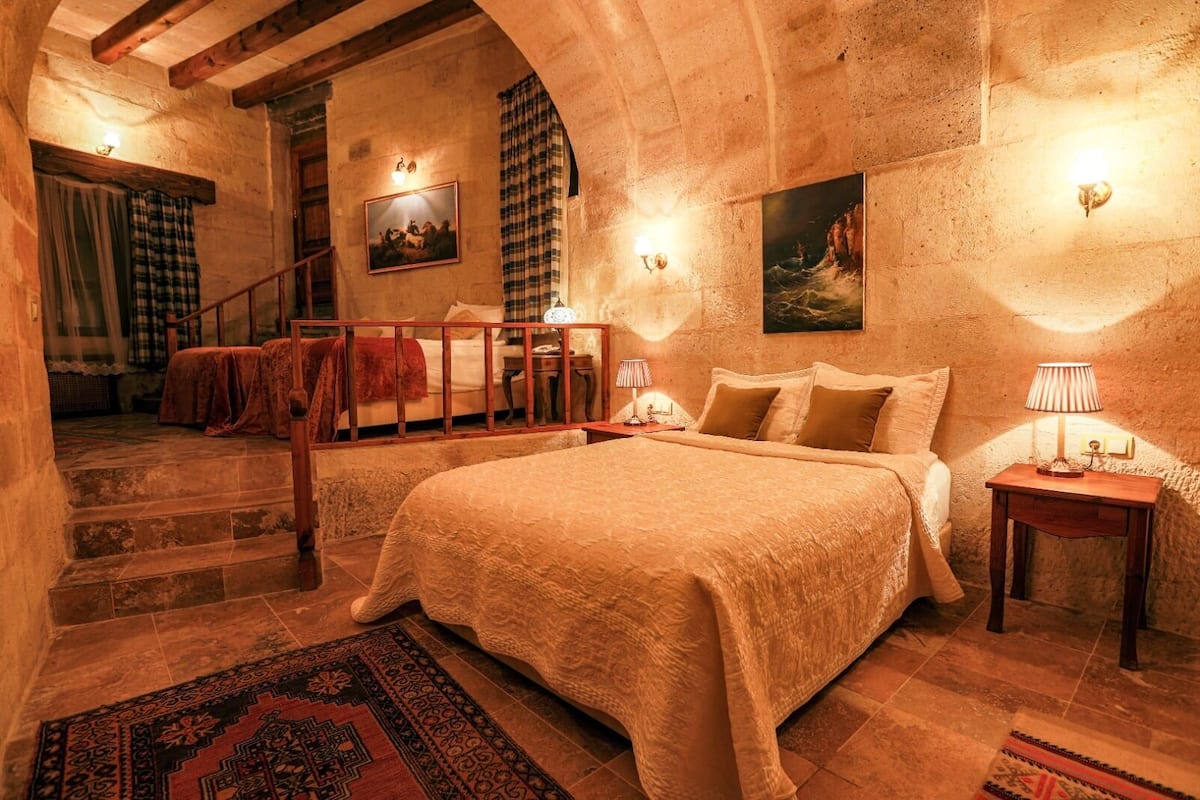 Ein gemütliches Schlafzimmer mit einem großen Bett, einer Holztreppe und einer rustikalen Steinwand.