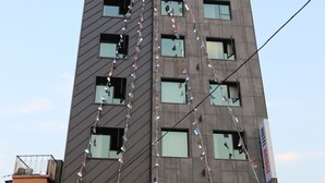 Un bâtiment d’hôtel moderne, avec une horloge sur la façade, de nombreuses fenêtres et une enseigne indiquant « HÔTEL BRIDGE ».