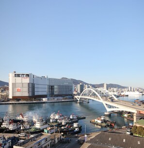 A harbor with boats, a bridge, and a modern building with a sign reading "LOTTE MALL". - Hotel Bridge (Busan)