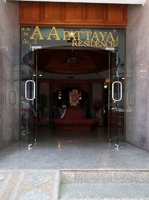 A hotel entrance with a glass door, a ceiling fan, and a statue in the lobby. - AA Pattaya Residence (Pattaya)
