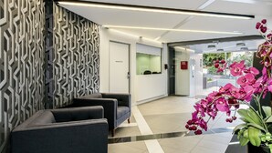 A reception area with a patterned wall, a reception desk, and a large orchid plant. - Code Apartments (Bowen Hills)