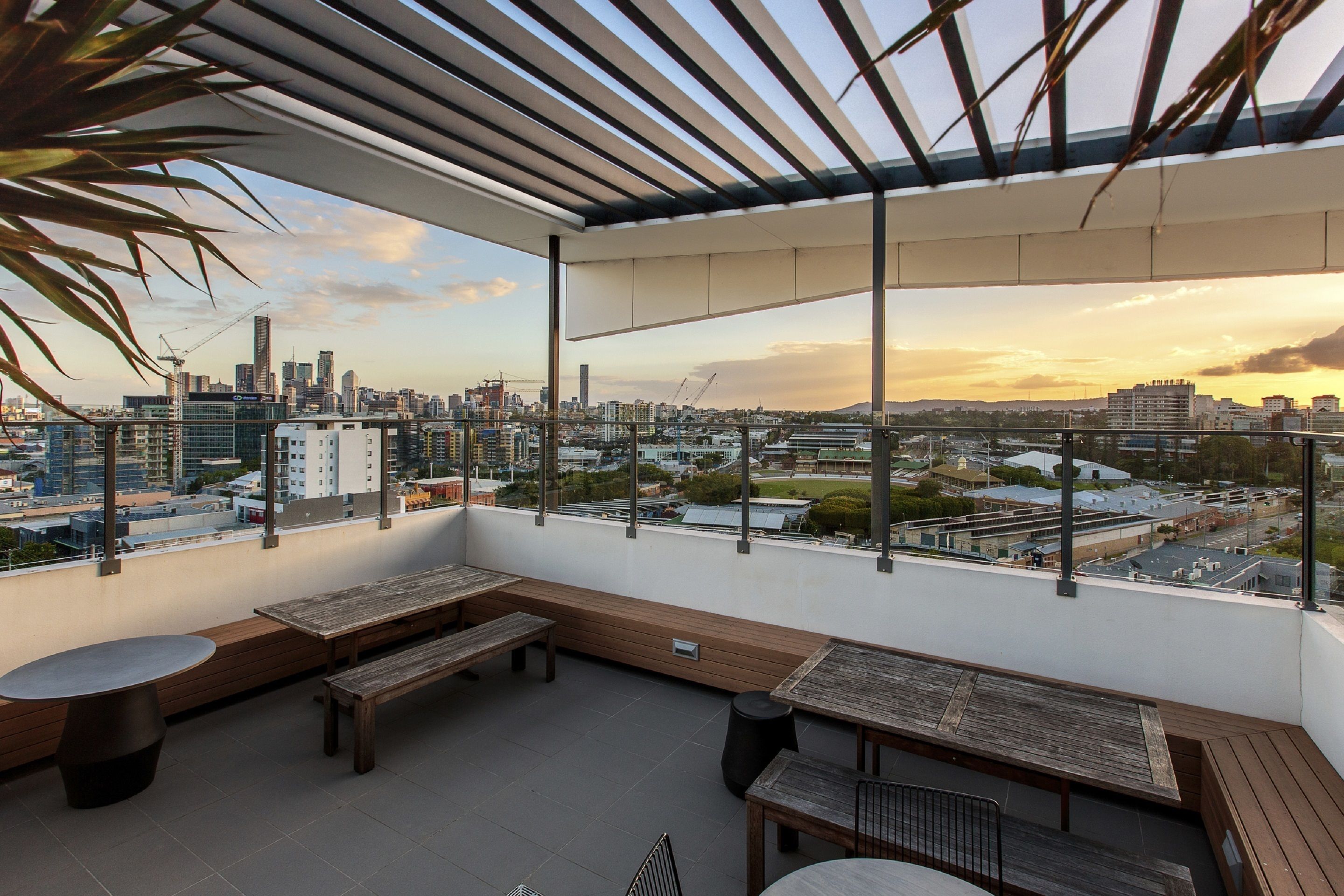 Terraza en la azotea con bancos y mesas de madera, con vistas a la ciudad.