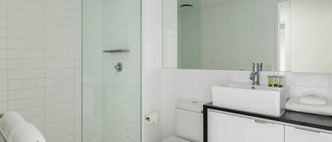 A modern bathroom with a glass-enclosed shower, a white toilet, and a sink with a black countertop.