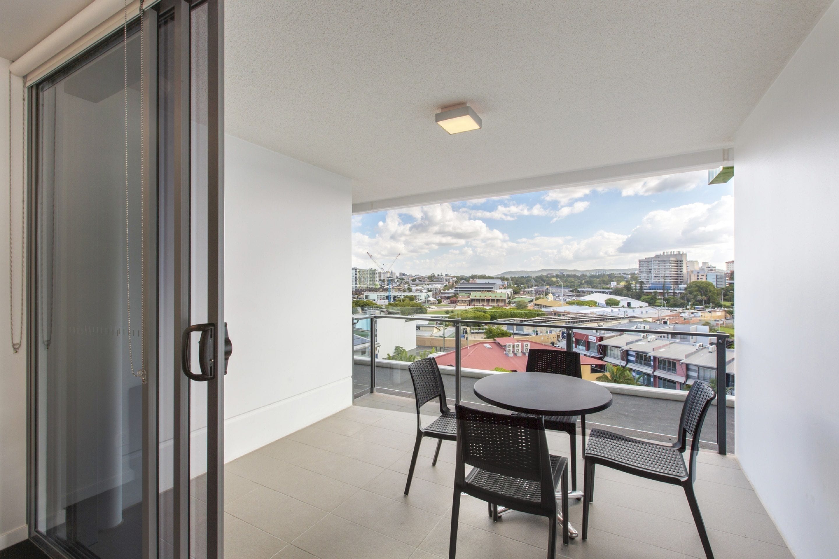 A balcony with a glass door, a round table, and two chairs.