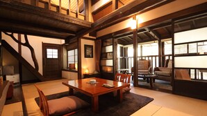 A traditional Japanese-style room with tatami flooring, a wooden dining table, and a low wooden bench. - Kurokawa Onsen Oyado Noshiyu (Minamioguni)
