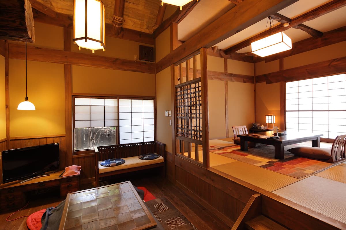 Ein traditioneller japanischer Raum mit Tatami-Boden, einem niedrigen Tisch, einer Couch und Schiebetüren.