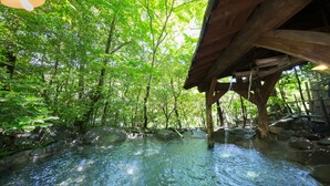 A serene outdoor pool area with clear water, surrounded by lush greenery and wooden structures. - Kurokawa Onsen Oyado Noshiyu (Minamioguni)