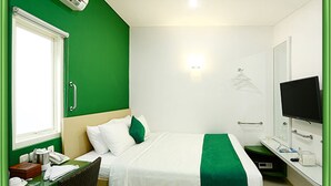 Habitación de hotel con cama, escritorio, teléfono, televisor y ventana.