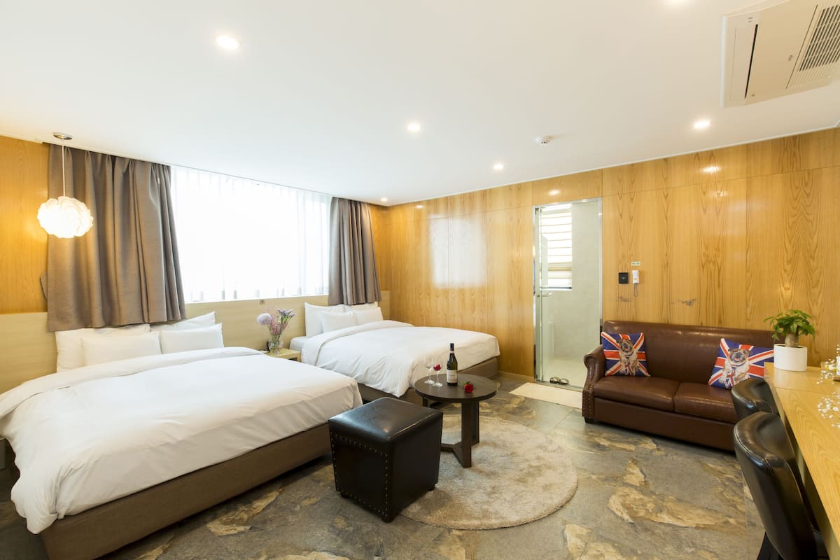 A hotel room with two beds, a sofa, a coffee table, and a small rug.
