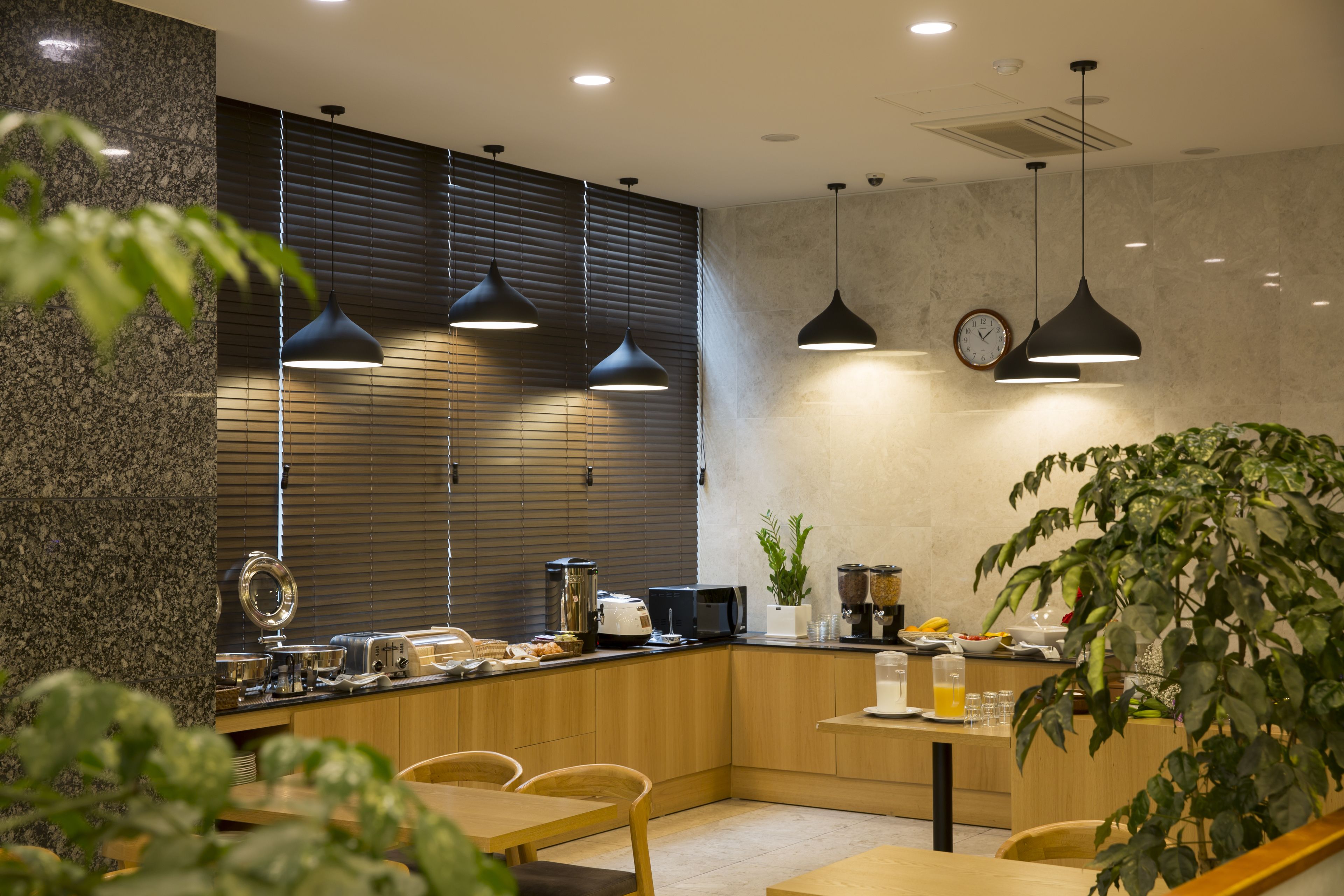 Una cocina moderna con encimeras de granito, armarios de madera e iluminación colgante.