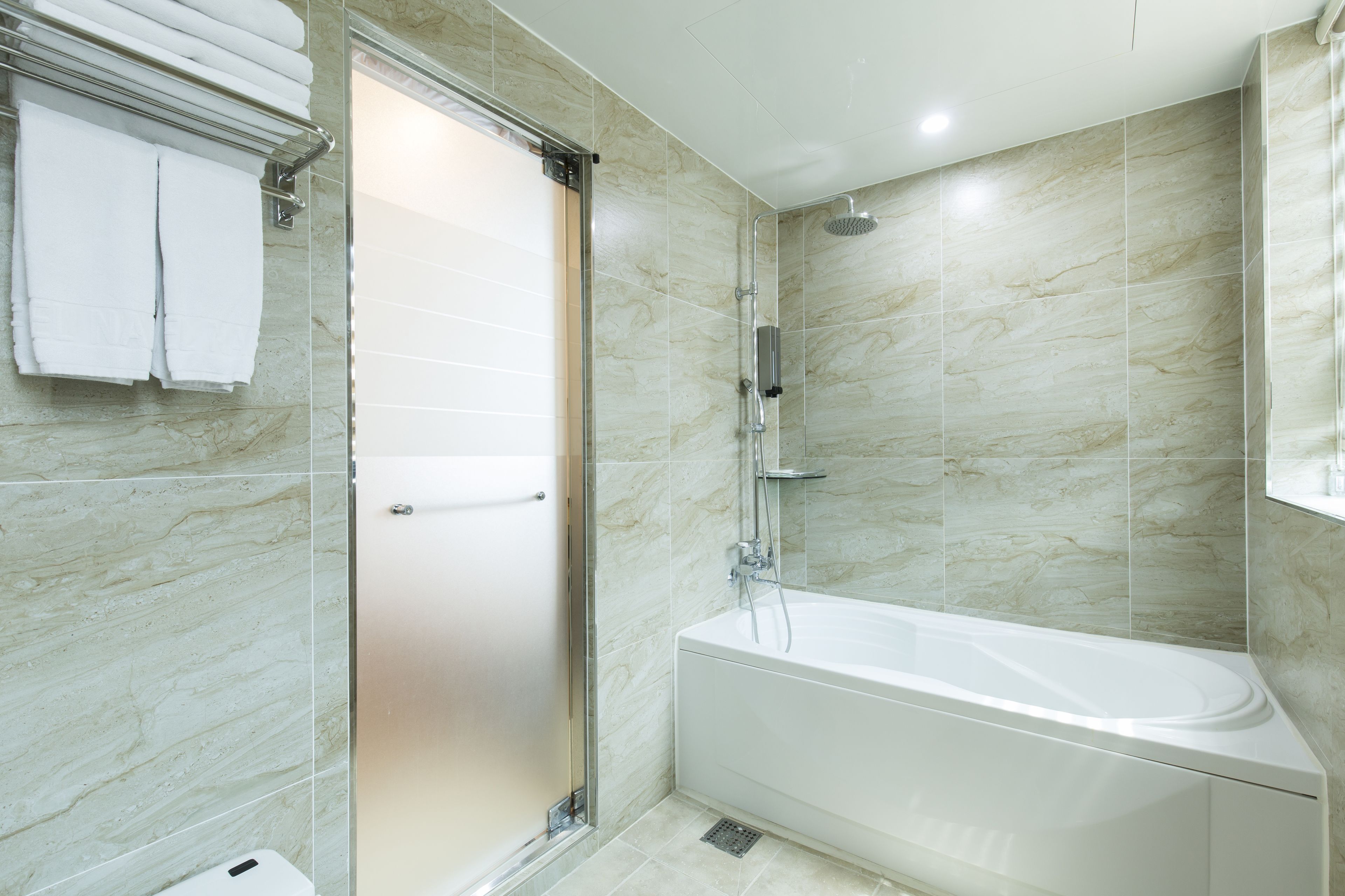 Un baño moderno con ducha envuelta en vidrio, una bañera independiente y un revestimiento de azulejos.