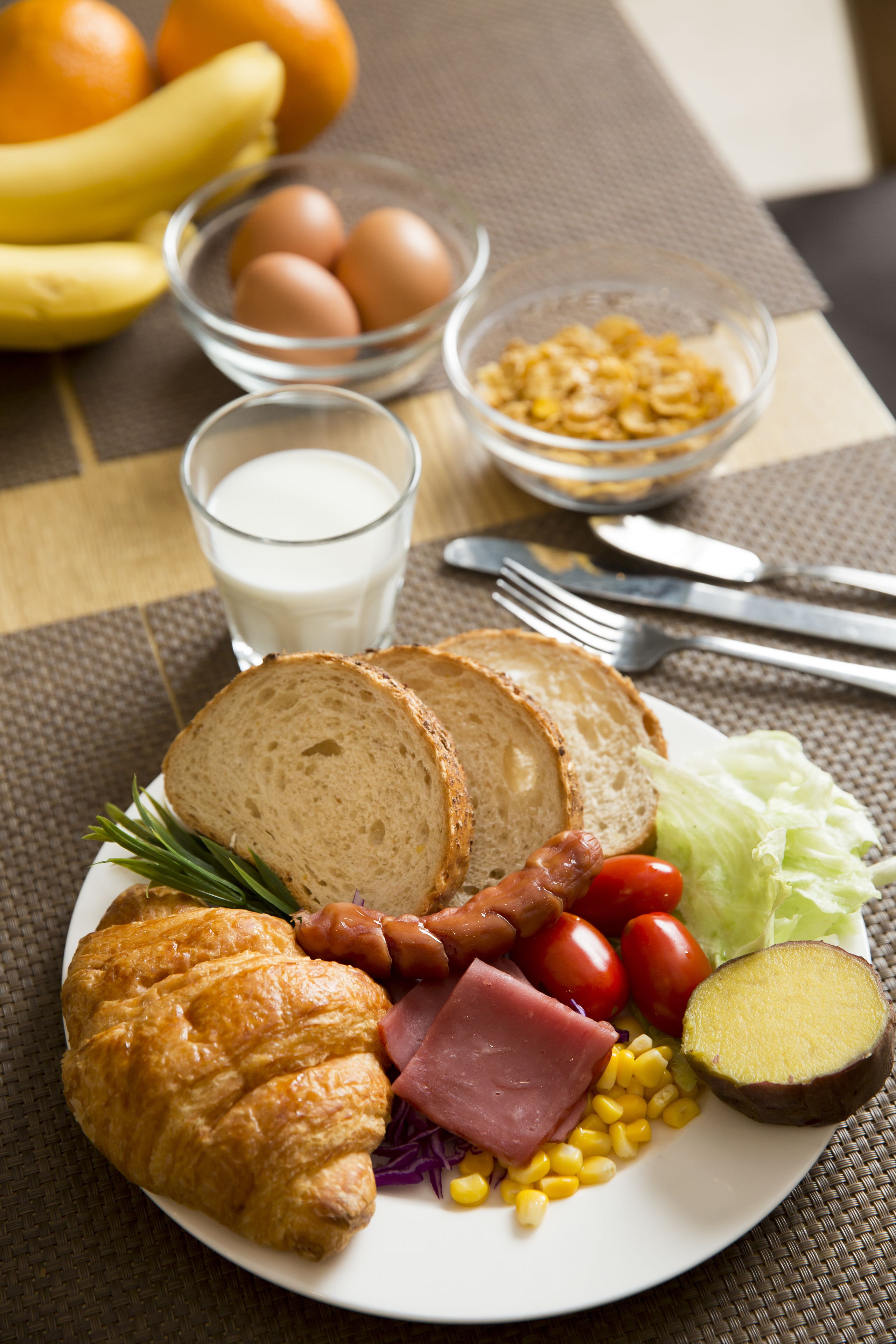 Un plat amb croissant, pernil, tomàquets, lletuga, blat de moro i una làmina de carbassa.