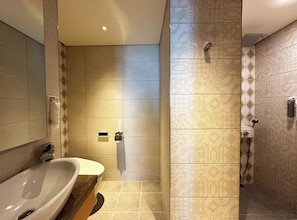 Bathroom features a bathtub, wall-mounted toilet, and shower area with handheld showerhead.