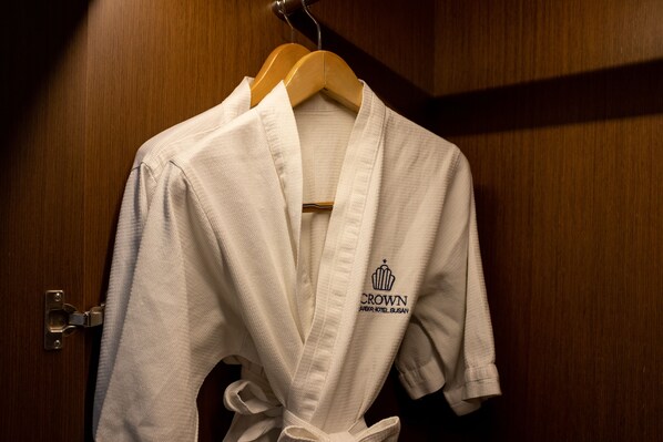 A white robe with a logo hanging on a wooden door.