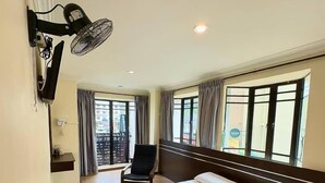 Una habitación de hotel con una cama grande, una silla, un escritorio y un ventanal con cortinas.