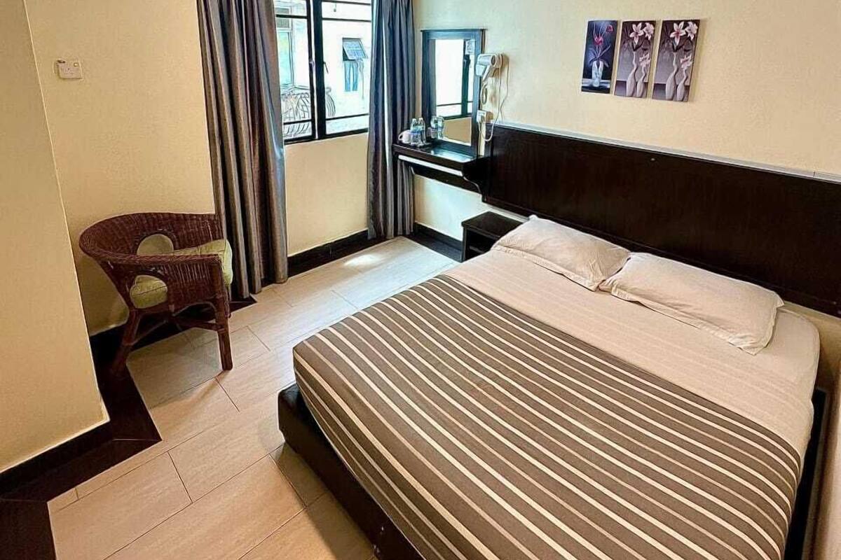 Une chambre d’hôtel avec un grand lit, un bureau, une chaise et une fenêtre avec des rideaux.