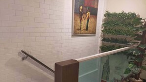 Una escalera con paredes de ladrillo blanco, barandilla de cristal y un cuadro de dos figuras tomadas de la mano.