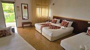 A hotel room with two beds, a bench, and a view of the garden. - Hotel Louro (Obidos)
