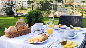 A breakfast table set outdoors with bread, pastries, coffee, and juice. - Hotel Louro (Obidos)