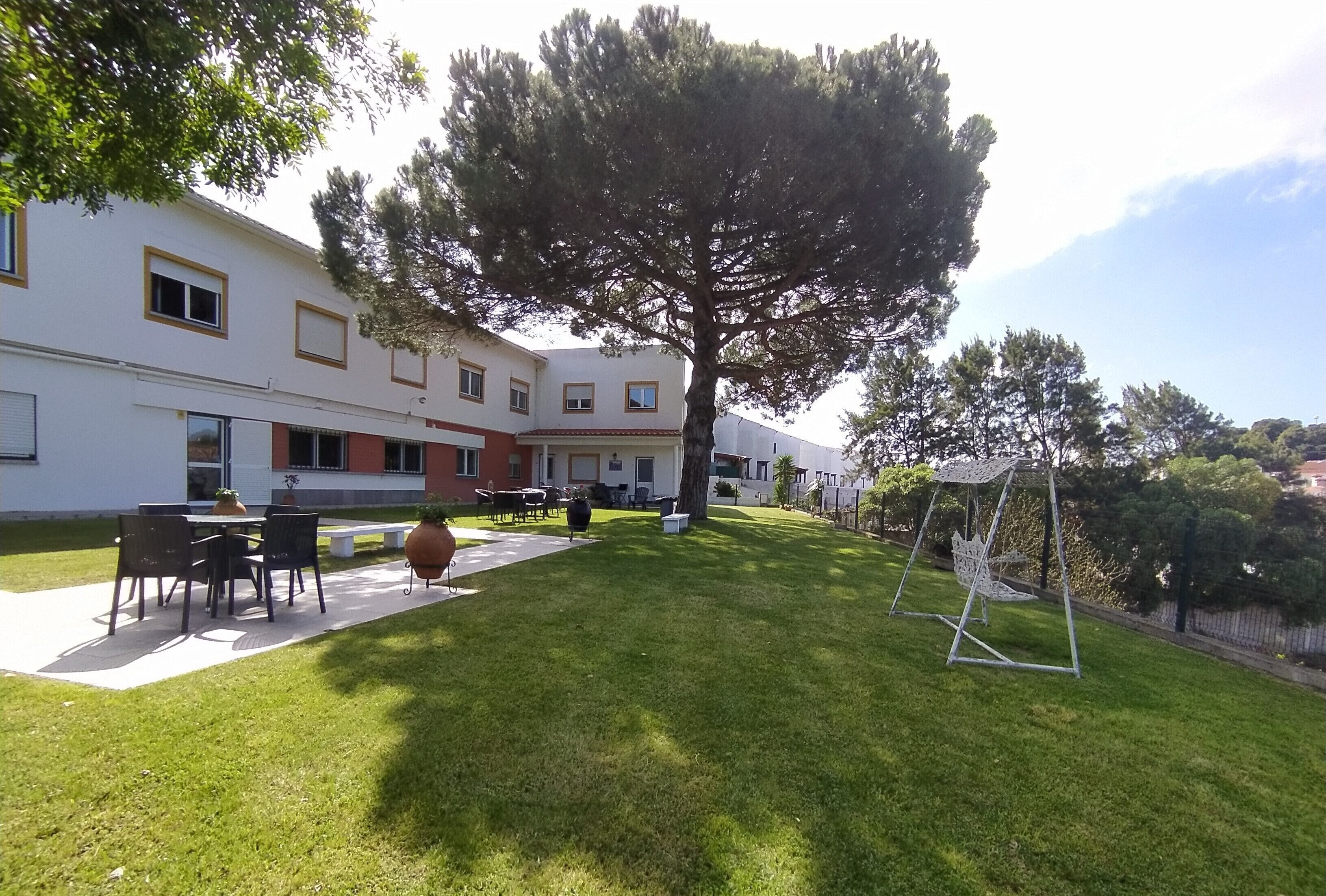 A courtyard with a large tree, outdoor seating, and a swing set.