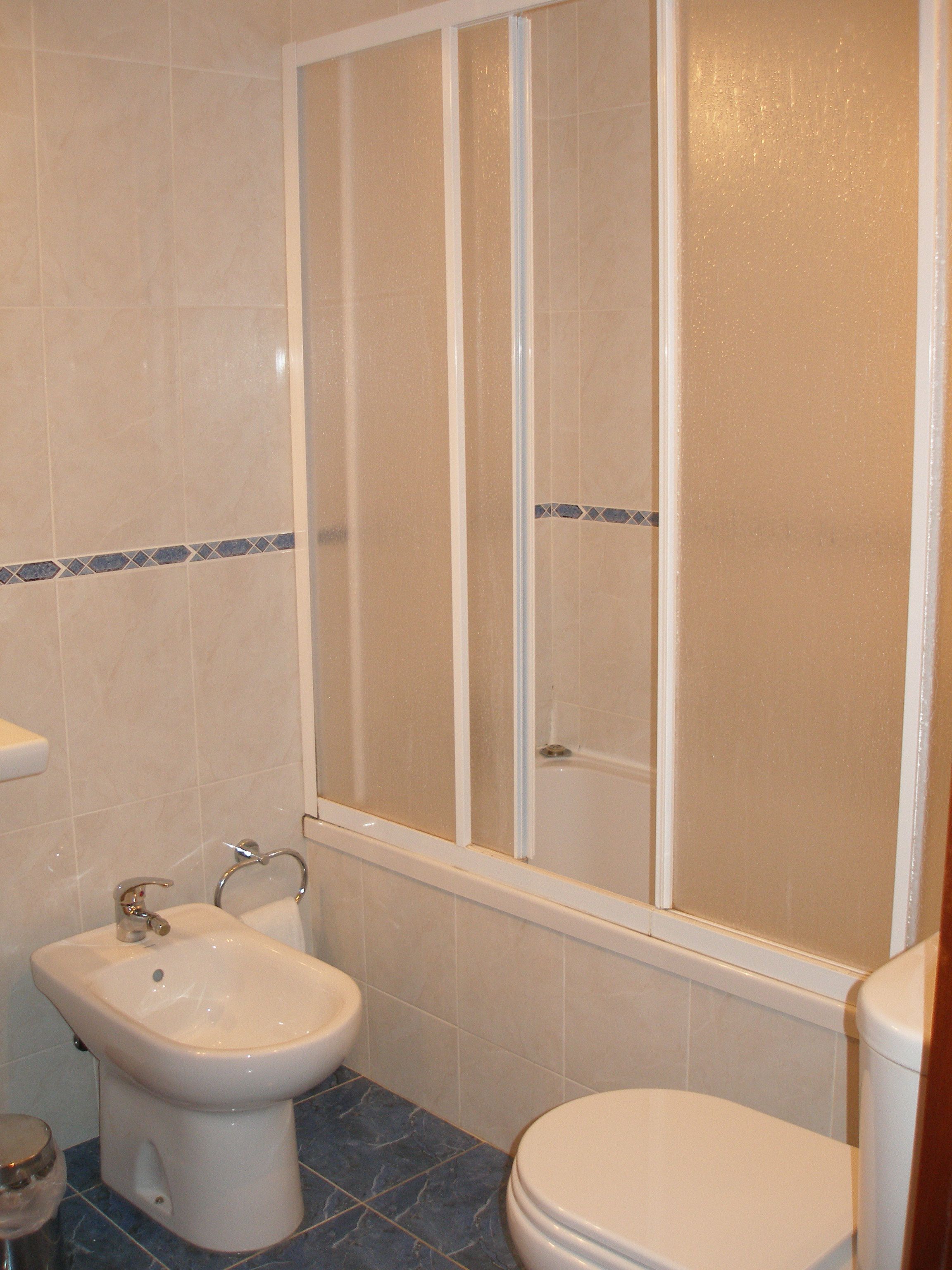 A bathroom with a shower enclosure, a bidet, and a toilet.