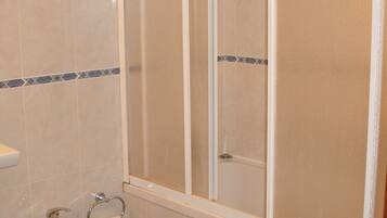 A bathroom with a shower enclosure, a bidet, and a toilet.