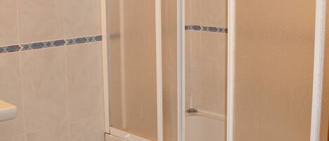 A bathroom with a shower enclosure, a bidet, and a toilet.