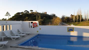 Una piscina al aire libre, sillones reclinables de piscina