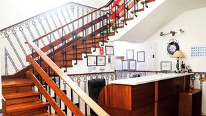 A wooden staircase with a metal railing leading to a reception desk area. - Hotel Louro (Obidos)