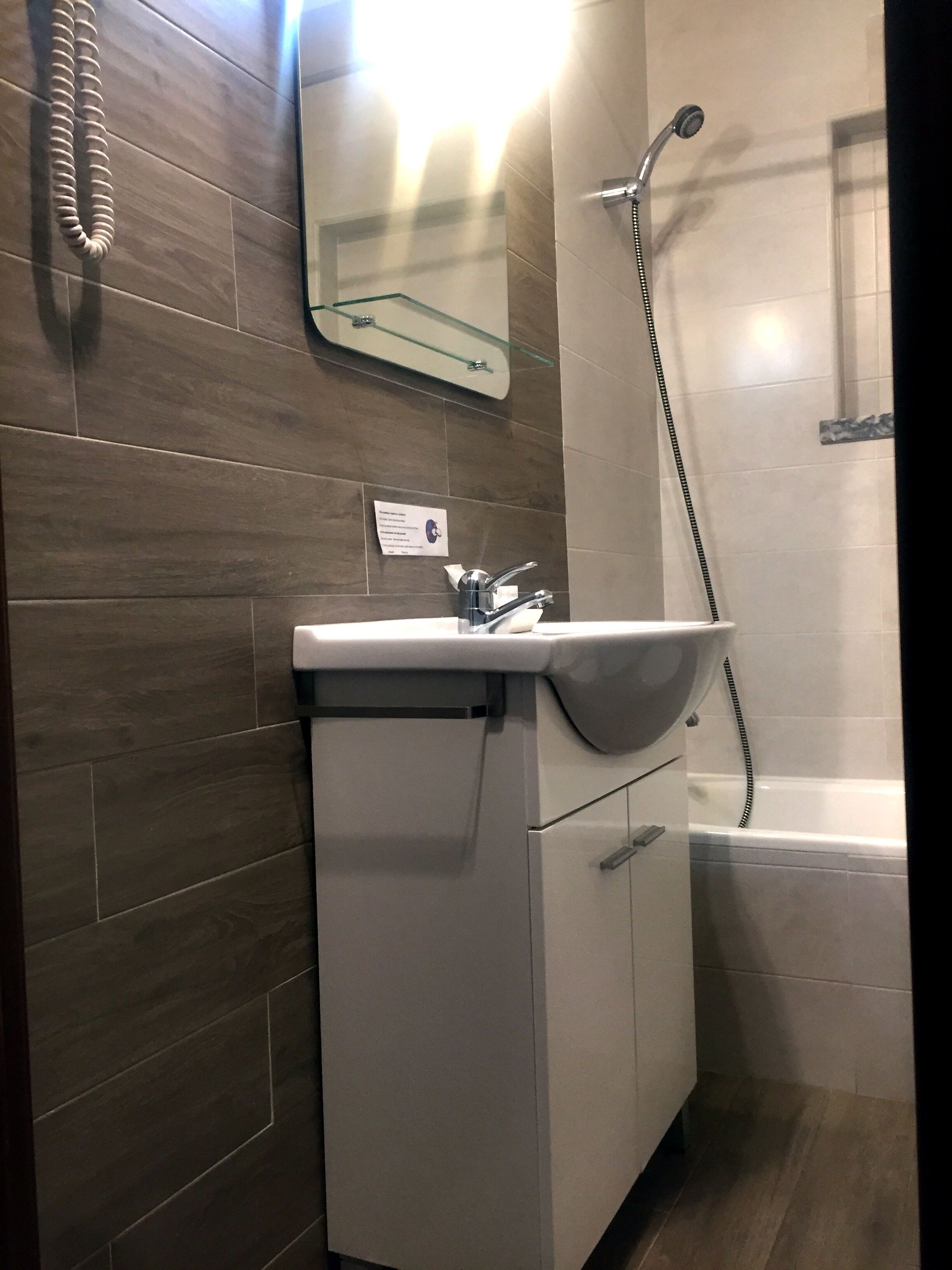 Un baño con lavamanos, espejo y ducha.