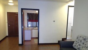 A living room with a sofa and a small table, a wooden floor, and a doorway leading to a kitchen area. - E Resort (Brinchang)